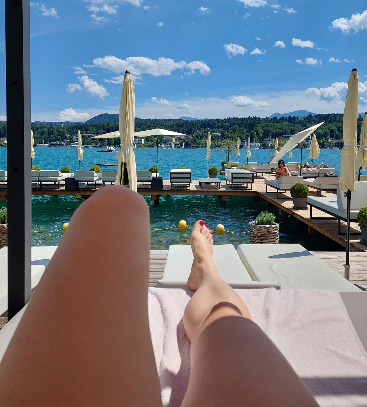 Pohľad na letnú terasu pri jazere Wörthersee, vedomá voľba medzi slnkom a tieňom